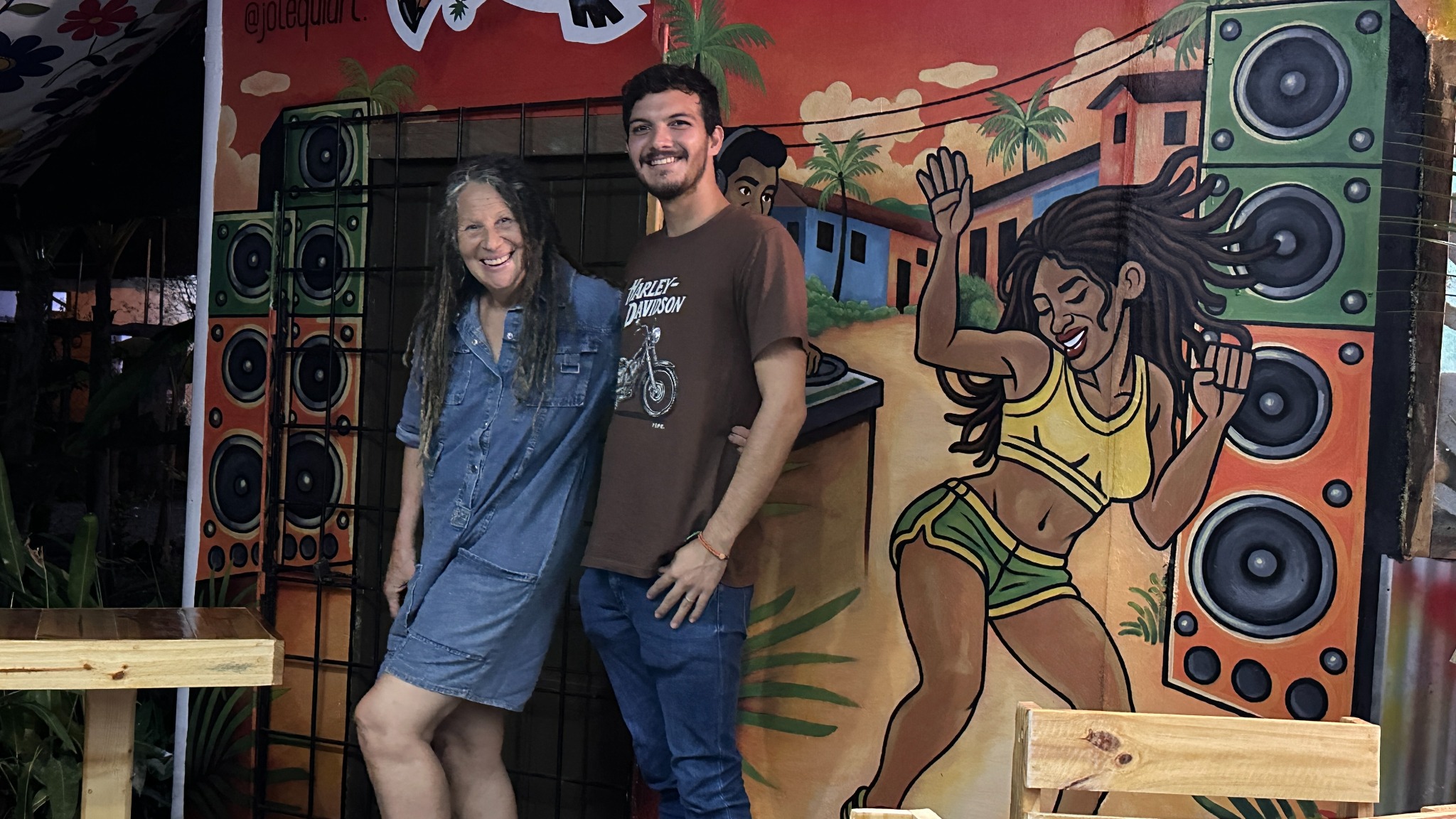 Guests posing beside the colourful reggae mural